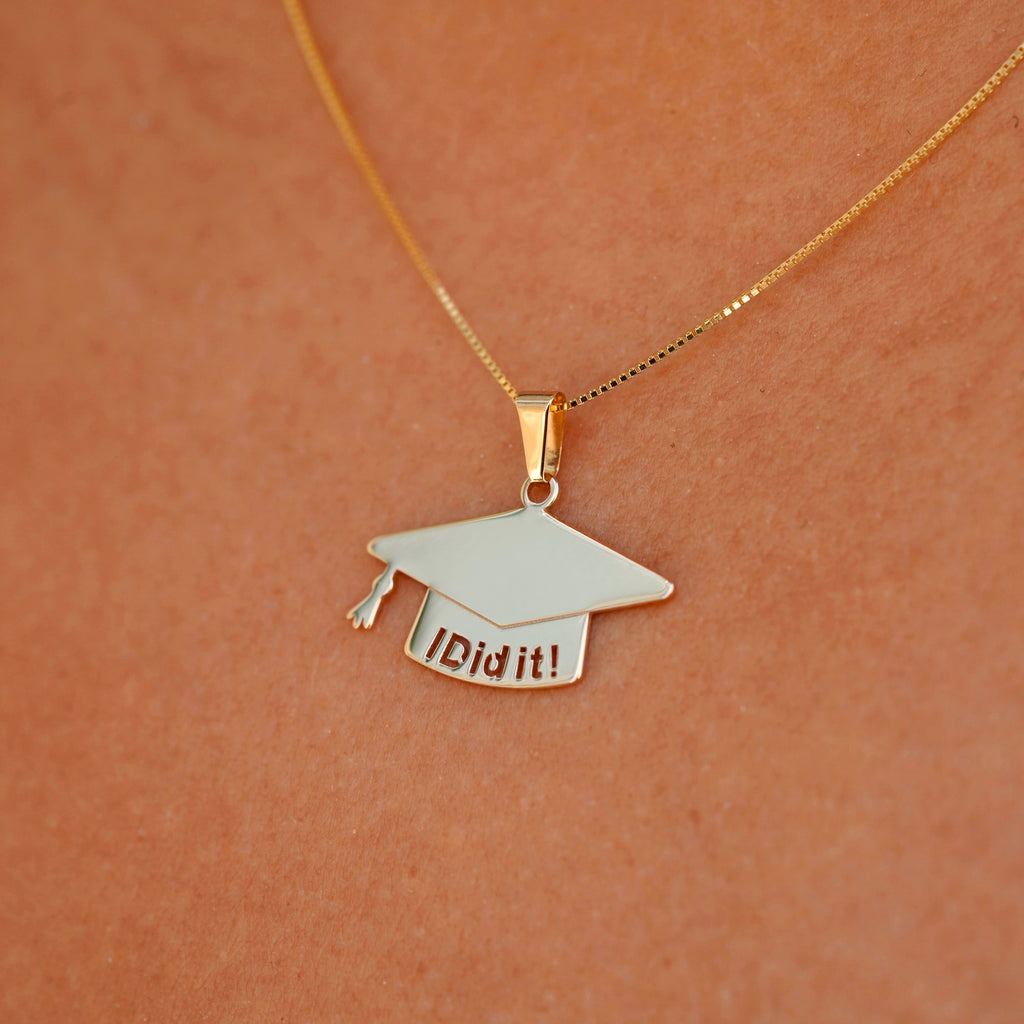 A model elegantly wears the 14K solid gold graduation cap pendant on a delicate chain, showcasing its brilliant shine and meaningful design. The charm rests beautifully against the skin, making it a perfect way to commemorate this special milestone.