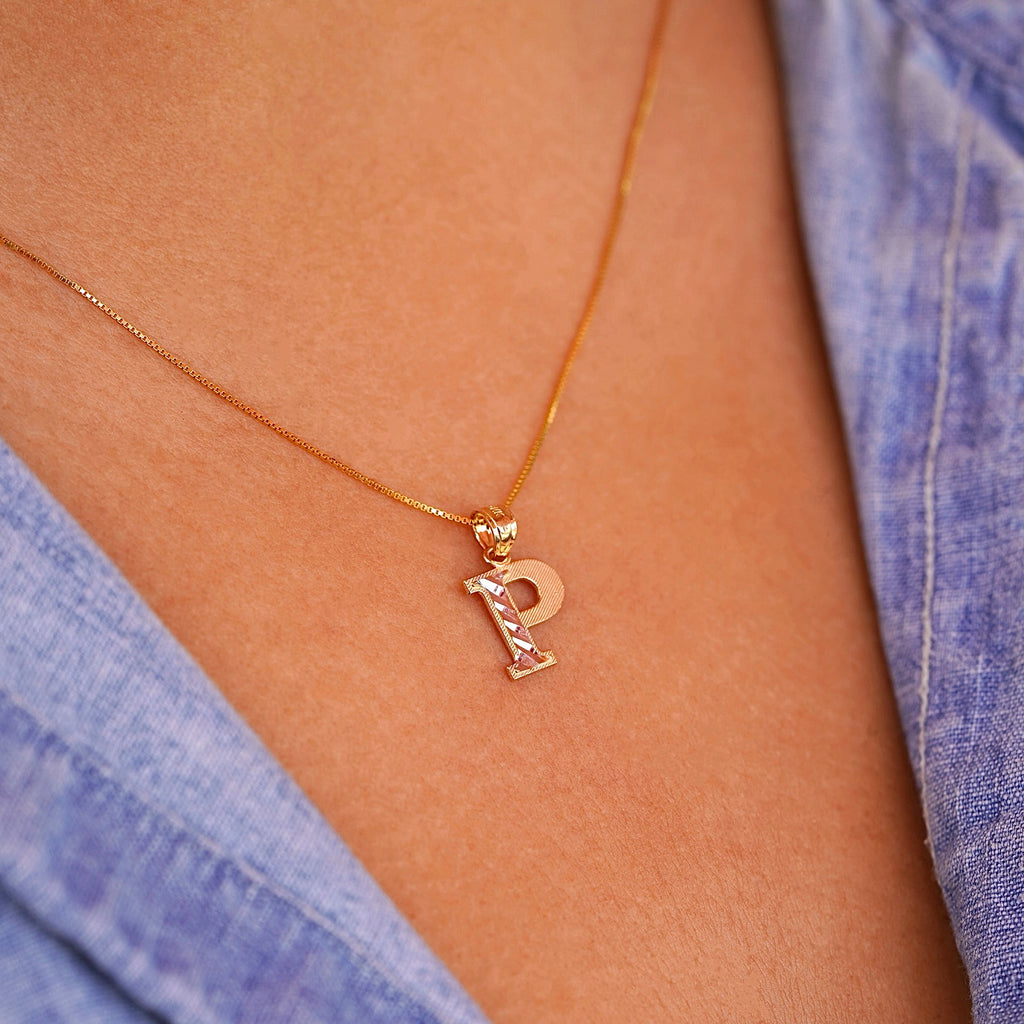 Model wearing a delicate 14K gold Initial P pendant necklace, layered with other fine chains for a personalized style statement.