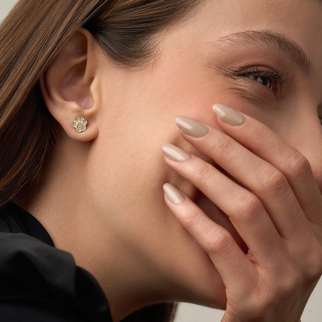 Model wearing 14K gold paw stud earrings featuring sparkling CZ stones, adding a delicate and meaningful touch to her everyday style.