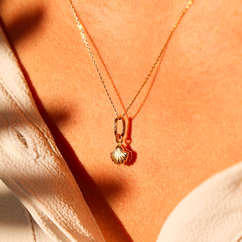 A woman elegantly wearing the 14K Solid Gold Pearl Pendant on a delicate gold chain, highlighting its timeless beauty and sophisticated design against her neckline.