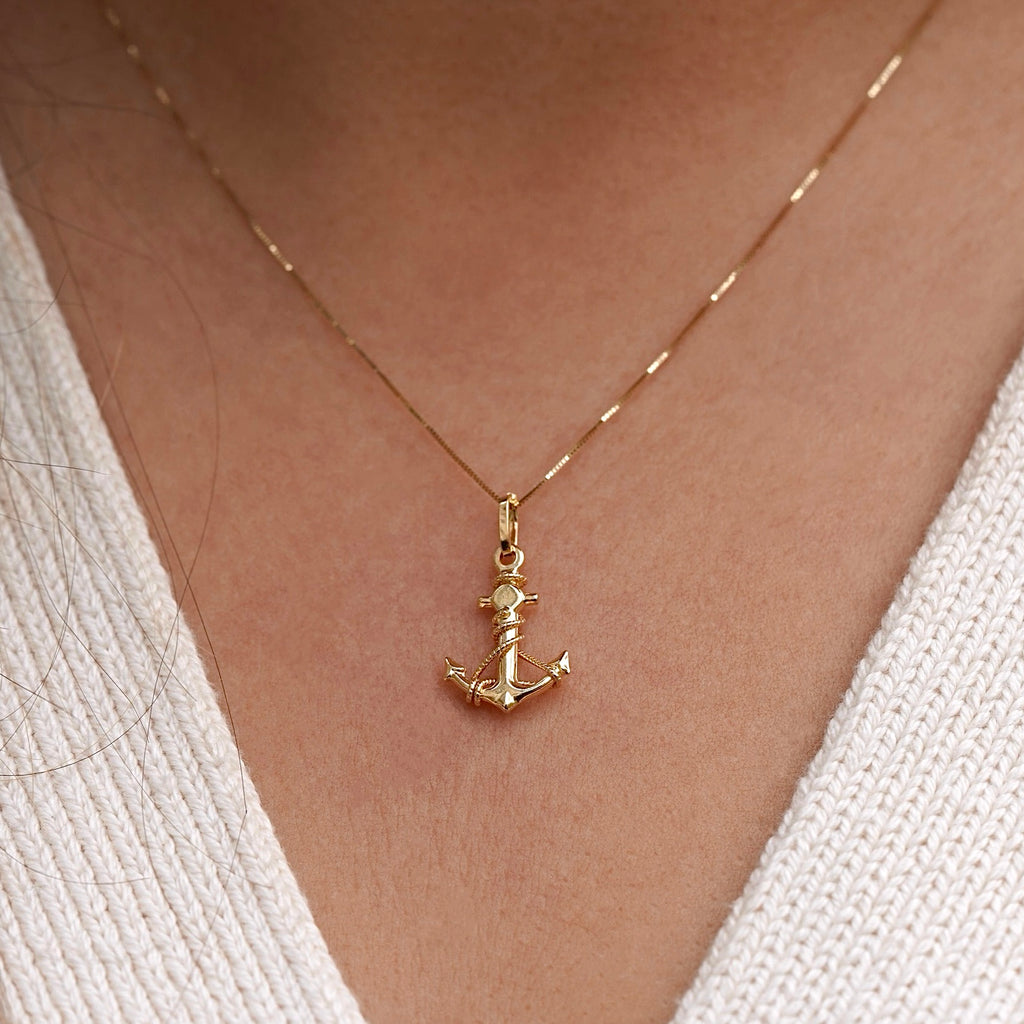 Model wearing a 14K gold anchor pendant on a delicate chain, showcasing the dainty nautical charm against the neckline for an elegant, maritime-inspired look.