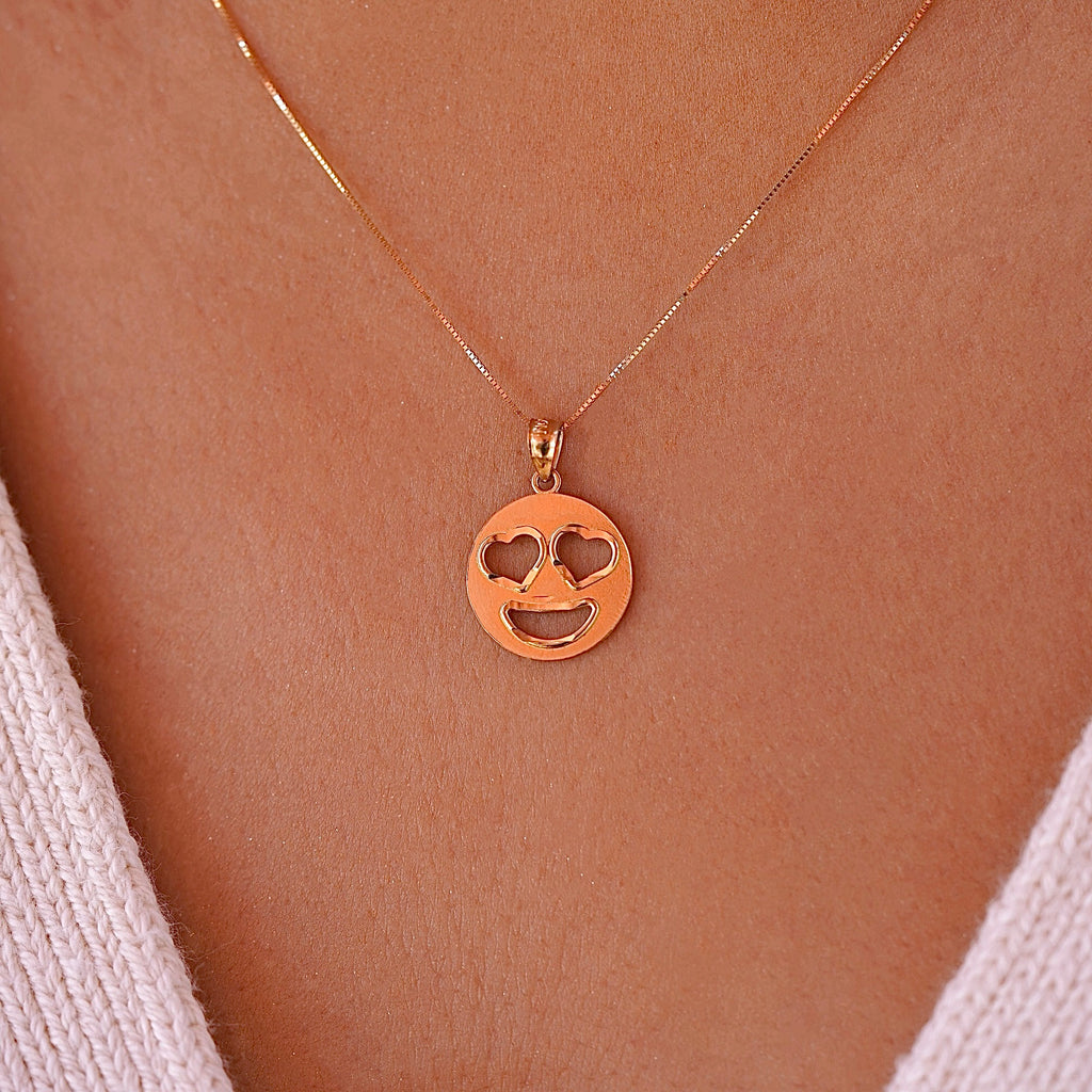Model wearing 14K gold heart eyes emoji pendant on a delicate gold chain, showing how the charm sits beautifully at the neckline for everyday elegance.