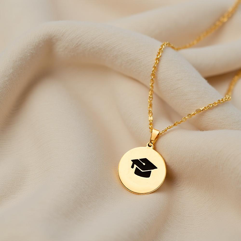 Elegant 14K Gold Graduation Pendant resting on soft off-white fabric, showcasing its refined craftsmanship and symbolic design.