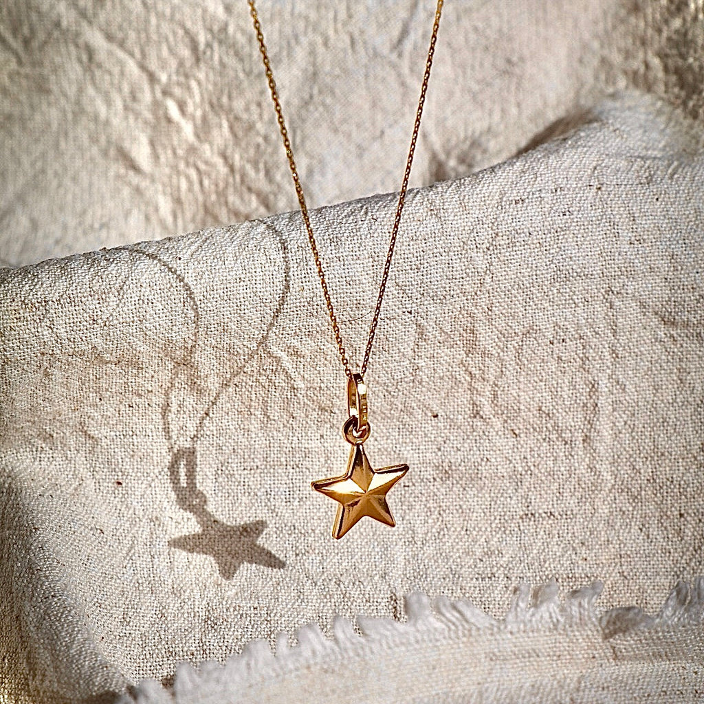 A delicate 14K solid gold starfish charm displayed against a white backdrop, showcasing its polished finish and intricate beach-inspired design.