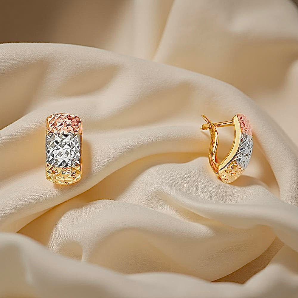 14K Tri-Color Half Huggies Earrings displayed on soft off-cream cloth, highlighting the delicate shine and intricate design of the petite gold hoops.