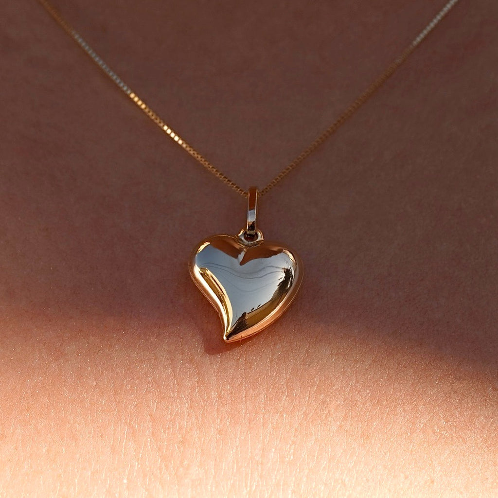 A model wearing the 14K Yellow Gold Hollow Heart Pendant on a fine chain, elegantly styled against her collarbone, highlighting its minimalist beauty.
