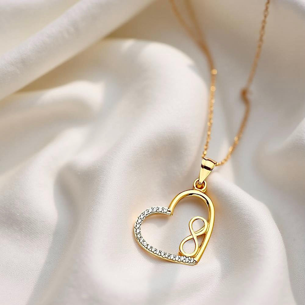 14K Gold CZ Heart Infinity Pendant resting on soft off-white cloth, highlighting its delicate curves and sparkling cubic zirconia in natural lighting.