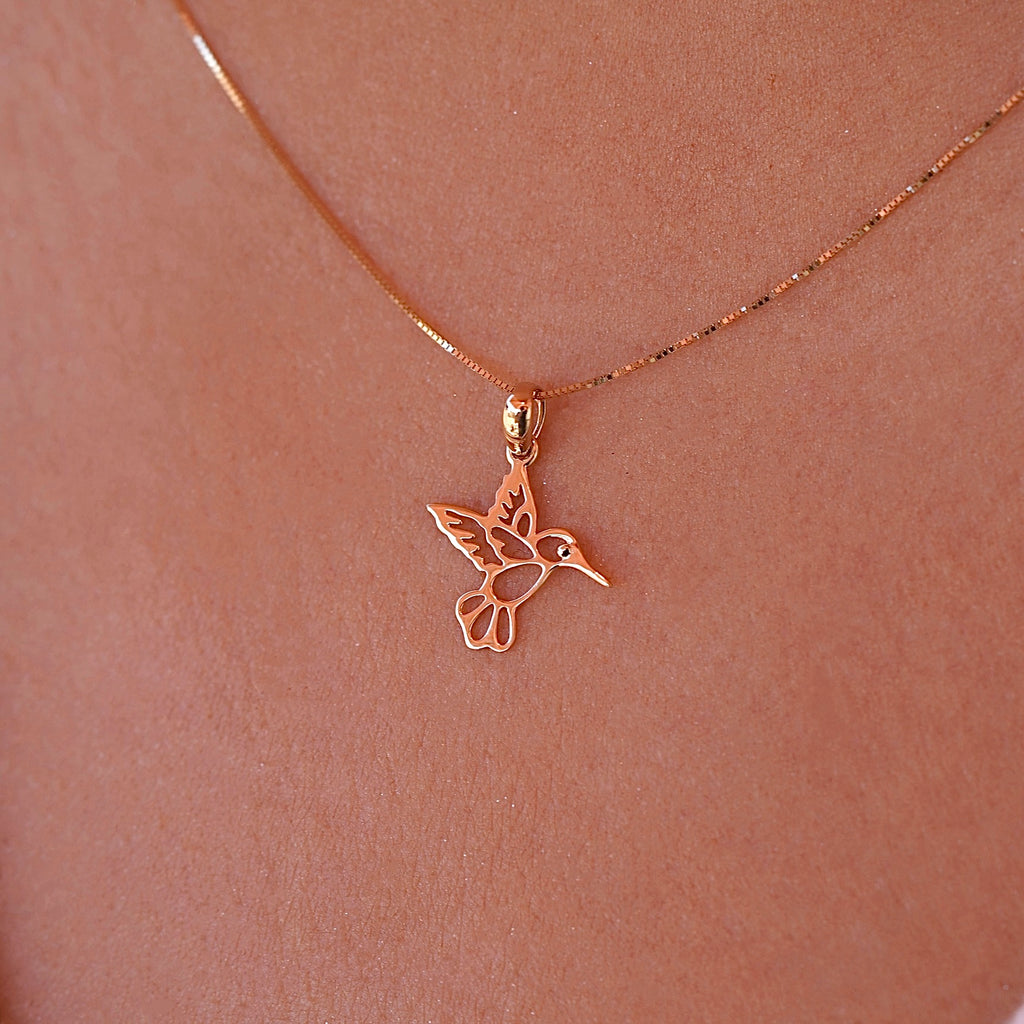 A model elegantly wears the 14K Yellow Gold Hummingbird Pendant on a delicate chain, highlighting its dainty size and the joyful charm it adds to her everyday style.