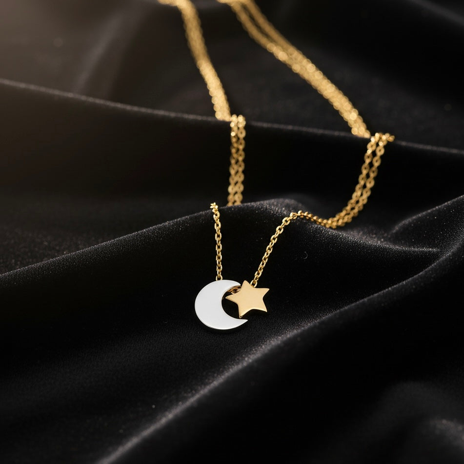 14K Two-Tone Gold Moon and Star Necklace elegantly laid on black velvet, highlighting the moon and star pendant and two-tone gold shine.