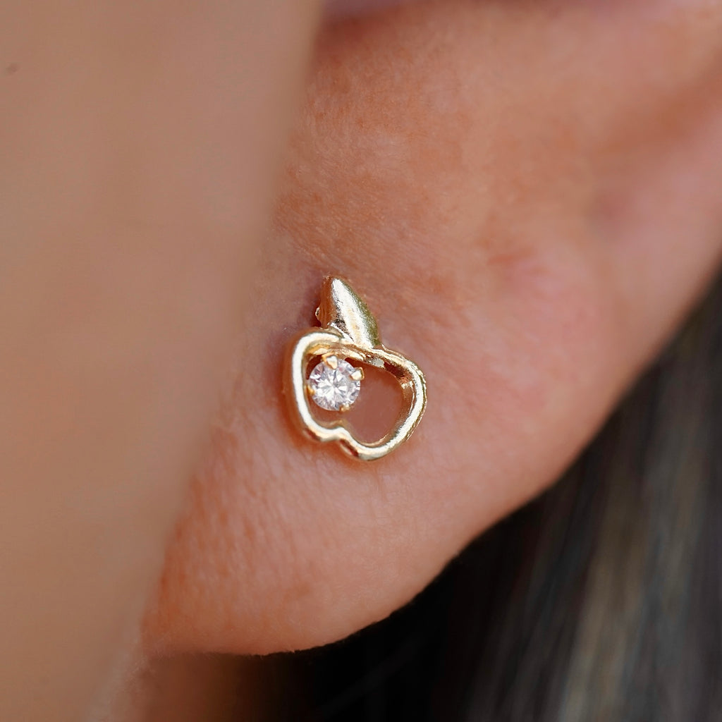 A close-up of a model wearing the 14K Gold Apple Stud Earrings, showcasing their dainty and minimalist design, adding a subtle sparkle to a casual yet chic outfit.