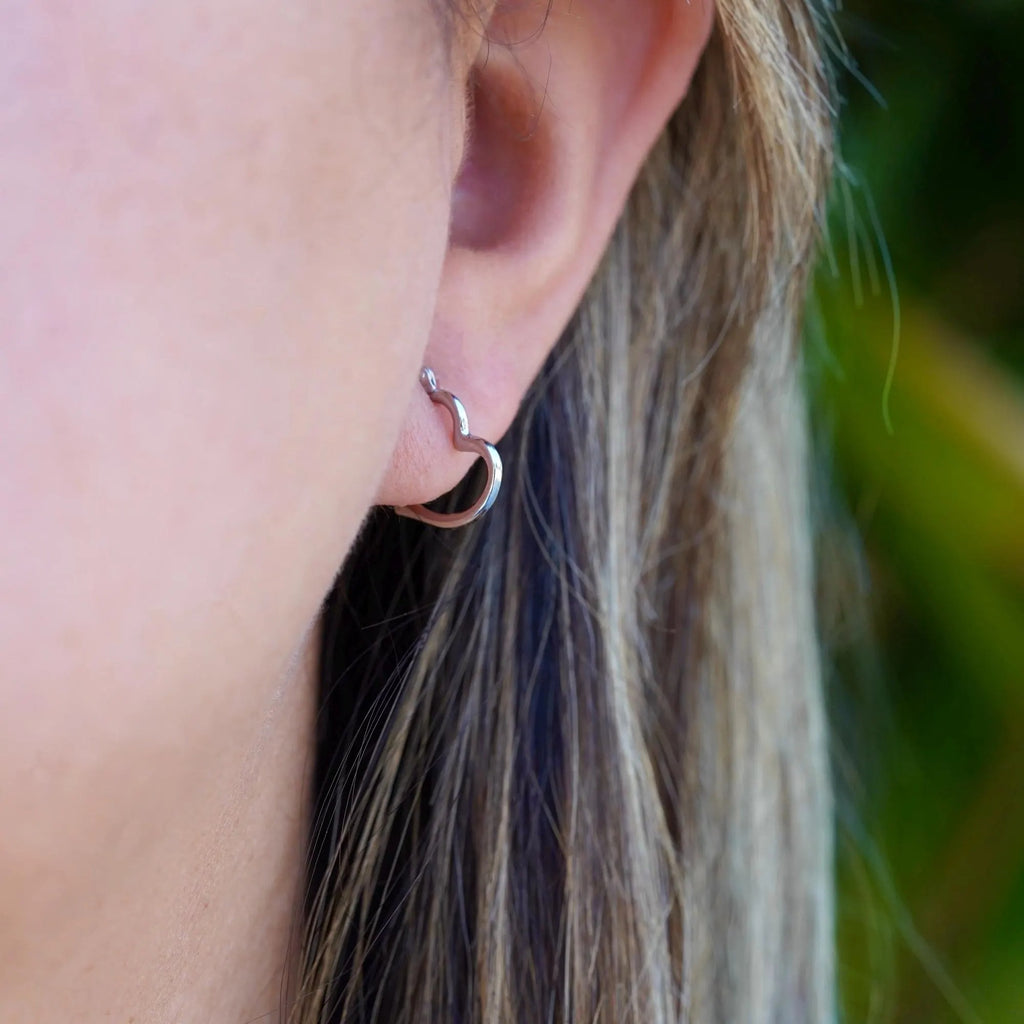 Model wearing dainty 14K white gold heart hoop earrings, with a radiant shine, highlighting the elegance and minimalist design of the earrings against a soft, natural background.