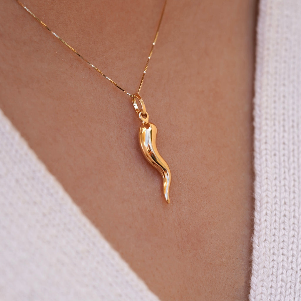 A model wears the 14K Yellow Gold Hollow Horn Pendant on a delicate chain, the pendant’s sleek, polished design resting gracefully on their chest. The hollow horn charm symbolizes protection and strength, adding a touch of elegance and spiritual significance to their look.