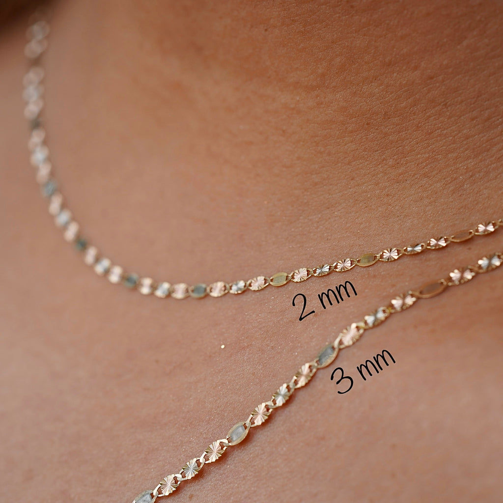 Close-up of the 14K tri-color 3mm Valentino Star Chain worn by the model.