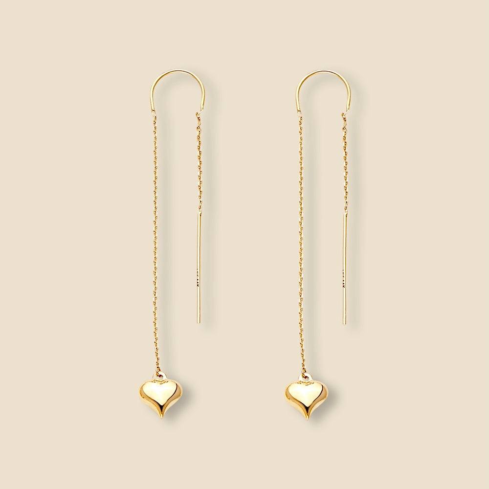 A pair of 14K yellow gold double-line heart earrings resting on plain background, highlighting the elegant 65mm drop length and minimalist open-heart silhouette with a polished, high-shine finish.