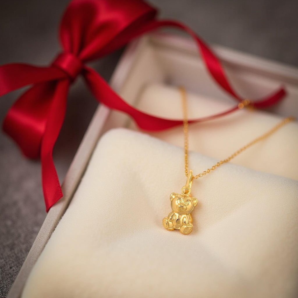 14K Gold Teddy Bear Charm Pendant displayed on a cream-colored velvet, highlighting its delicate details and warm golden glow.