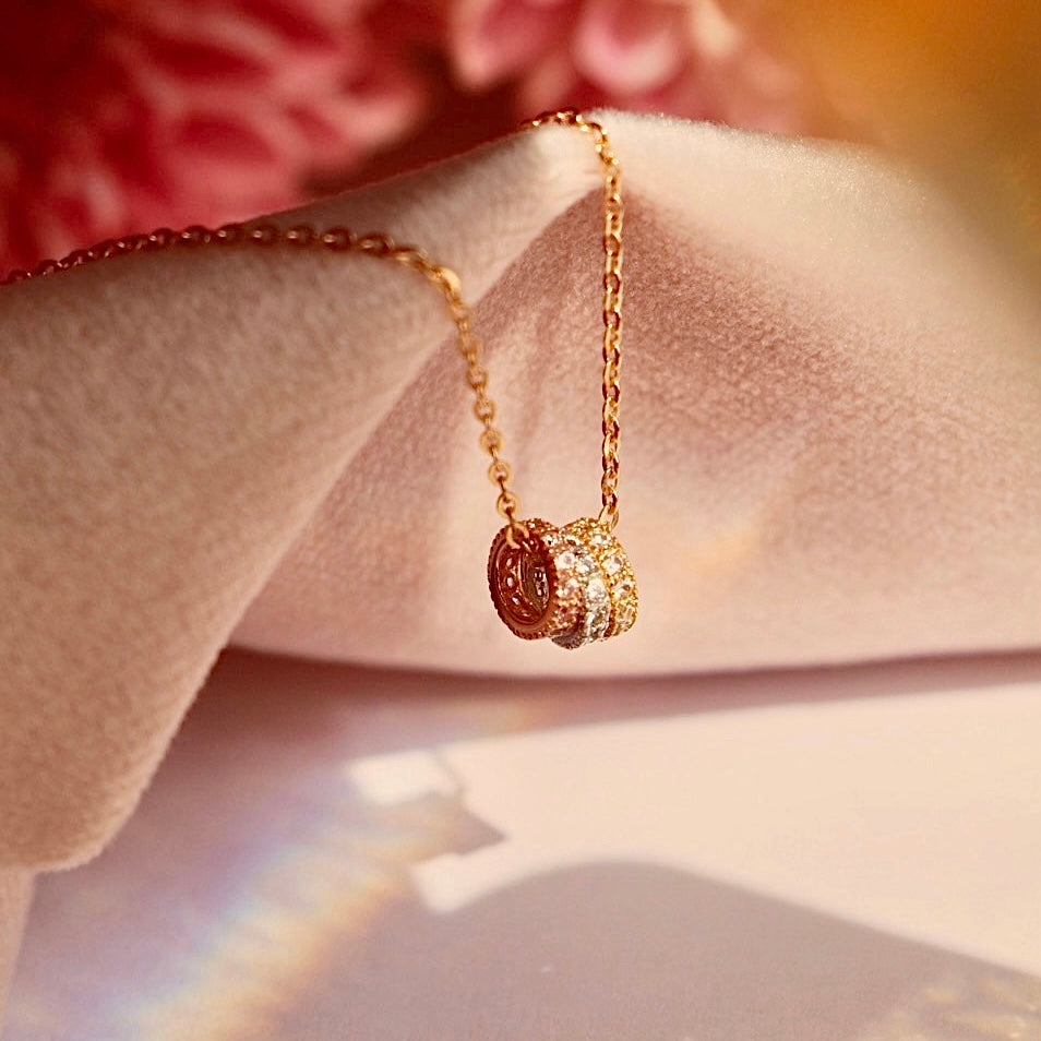 A delicate Circles 14K Solid Gold Necklace displayed against a soft pink background, highlighting its elegant tri-color gold design and fine craftsmanship. The perfect gift for layering or everyday wear.
