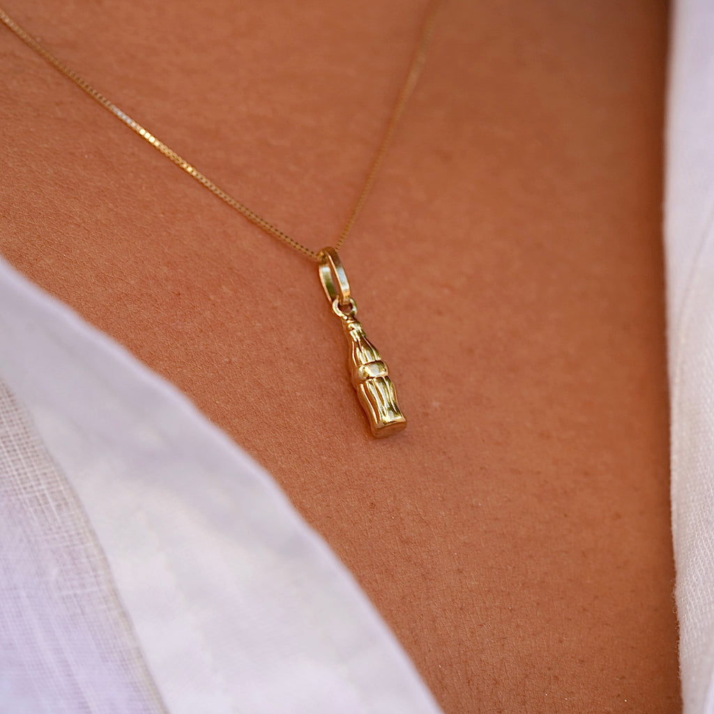 A close-up of a model wearing the 14K solid gold soda bottle pendant on a delicate chain, emphasizing its dainty and playful charm.