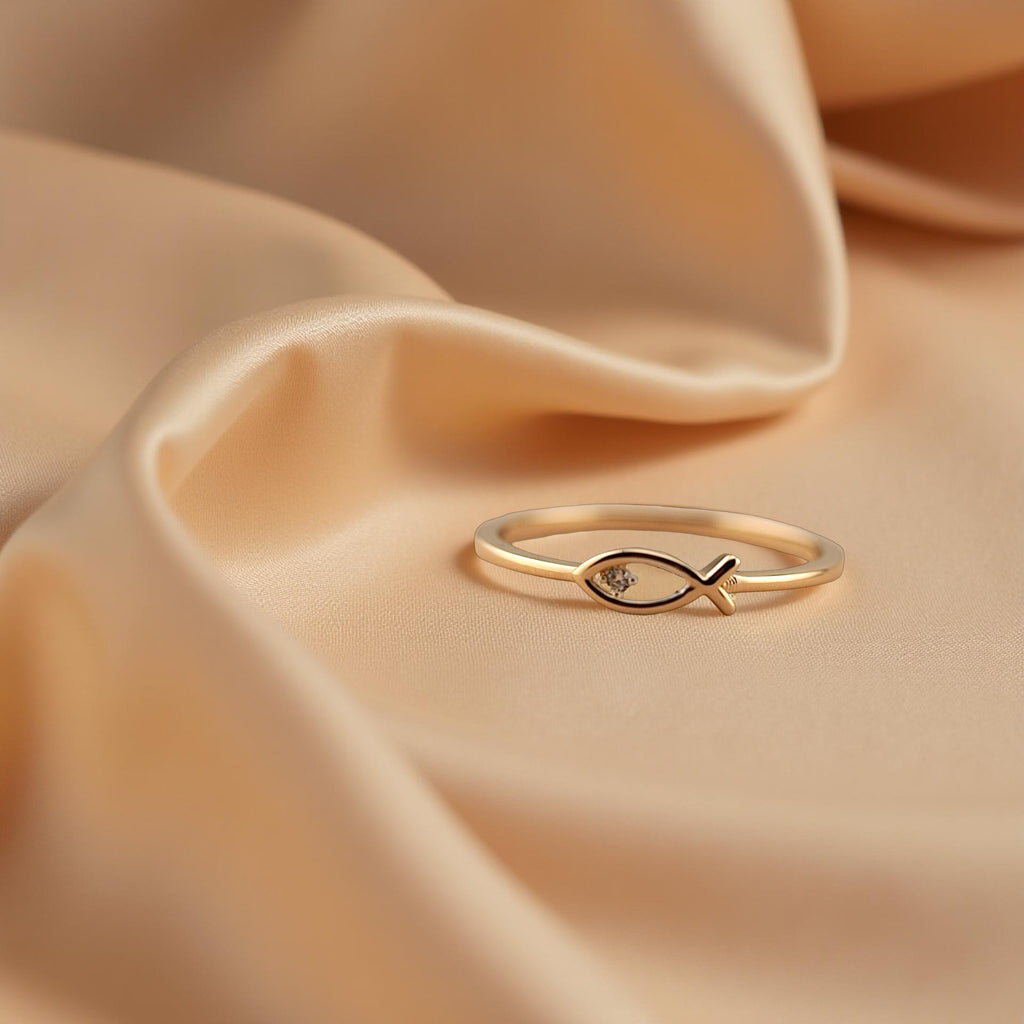 Minimalist Christian fish ring made from solid 14K yellow gold, displayed on a beige cloth with a luxurious golden shine.