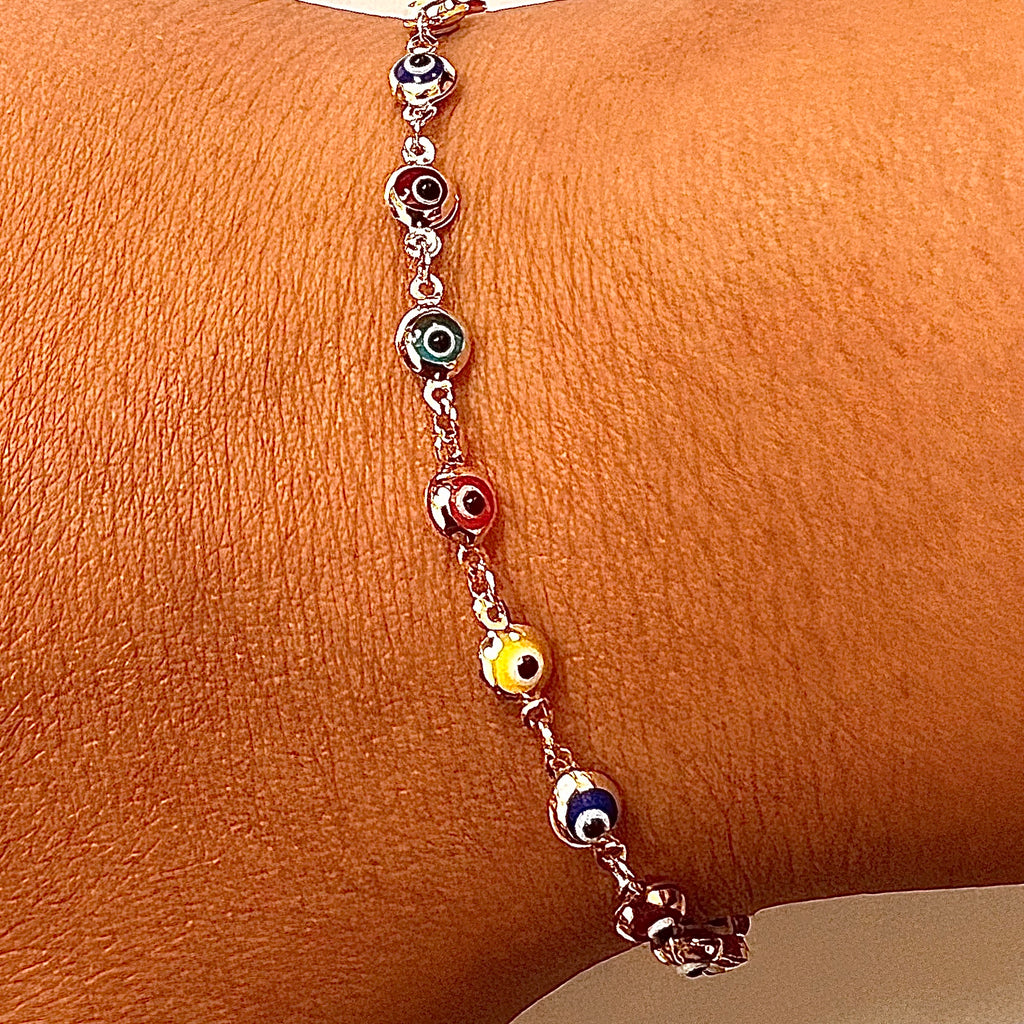 Model wearing a 14K gold mixed color evil eye bracelet on wrist, highlighting its colorful charms and delicate design as part of a stylish everyday jewelry look.