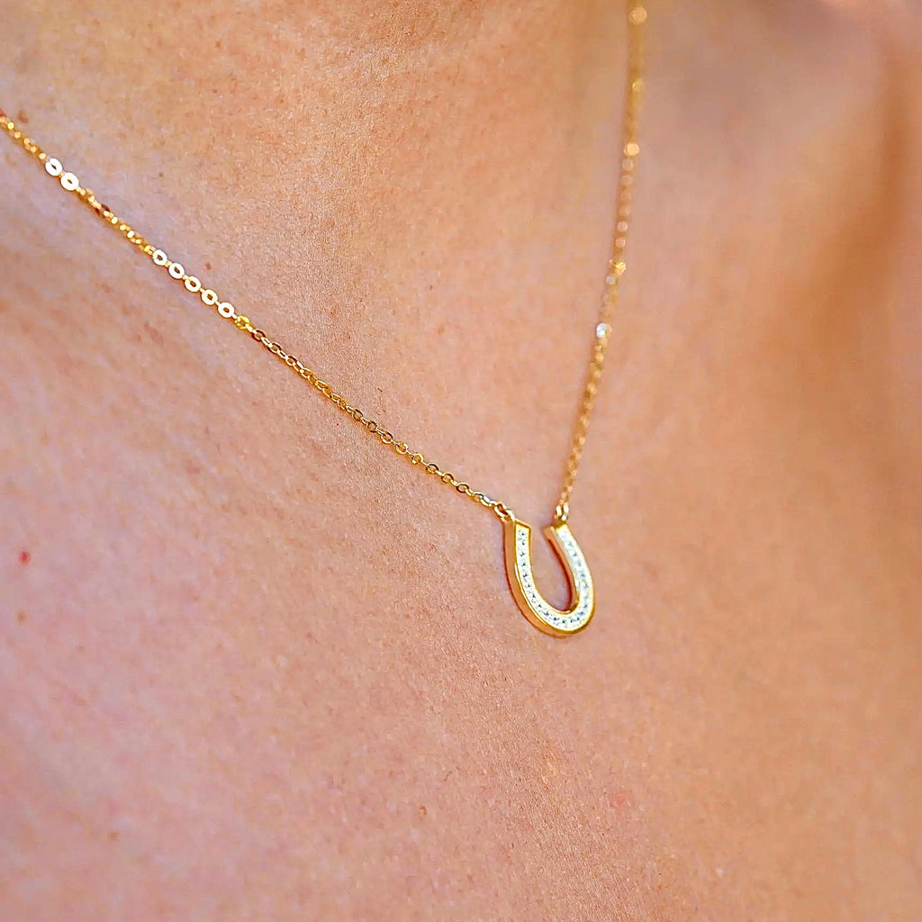 A model gracefully wears the 14K Solid Gold Horseshoe Necklace, showcasing its dainty and elegant design. The polished horseshoe pendant rests beautifully against the collarbone, adding a touch of luck and sophistication to any outfit. Perfect for layering or wearing alone as a meaningful statement piece.