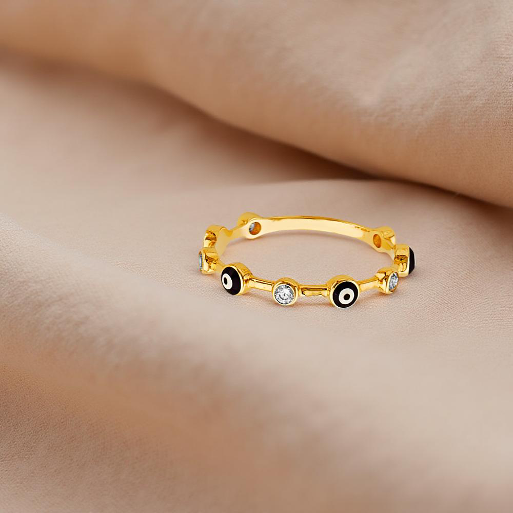 Close-up of a dainty 14K gold evil eye ring resting on textured neutral fabric, showcasing the sparkling blue cubic zirconia set within the classic evil eye design.