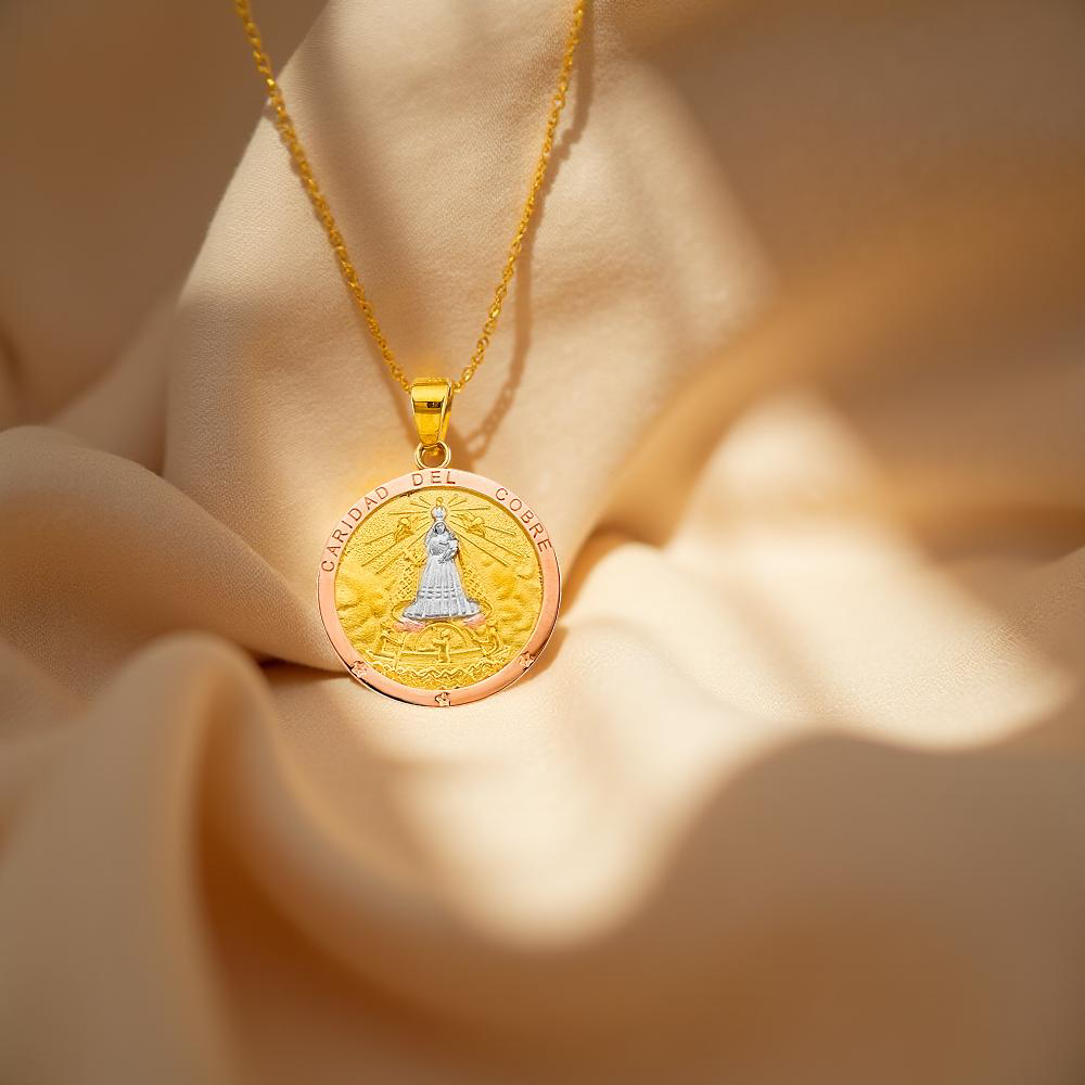 Elegant Cuban Caridad del Cobre pendant in rose, white, and yellow gold, placed on a neutral linen cloth, highlighting the intricate detailing and rich spiritual symbolism of this religious charm.