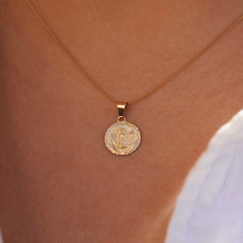 A model wears the 14K gold religious stamp pendant on a fine chain, the charm resting gently near the collarbone, blending timeless faith with everyday elegance.