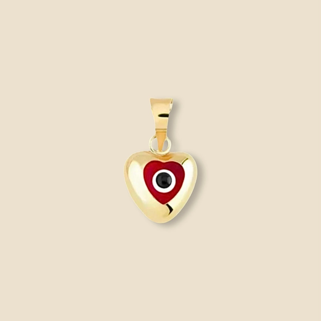 The 14K solid gold evil eye heart charm with a deep red enamel eye is showcased on a plain background, highlighting its warm gold tone and protective symbolism with a touch of fiery elegance.