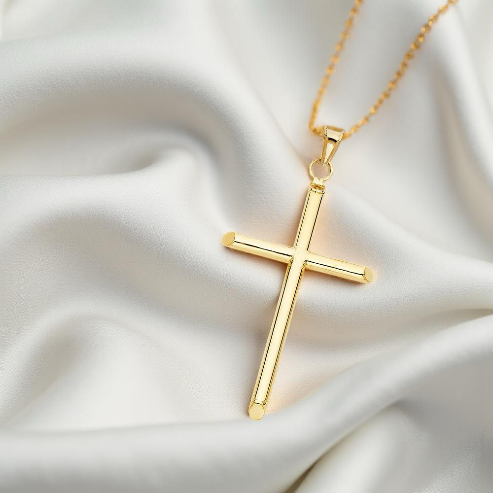 Elegant 14K gold cross charm displayed on soft off-white fabric, showcasing its large proportions and luminous finish under soft lighting.