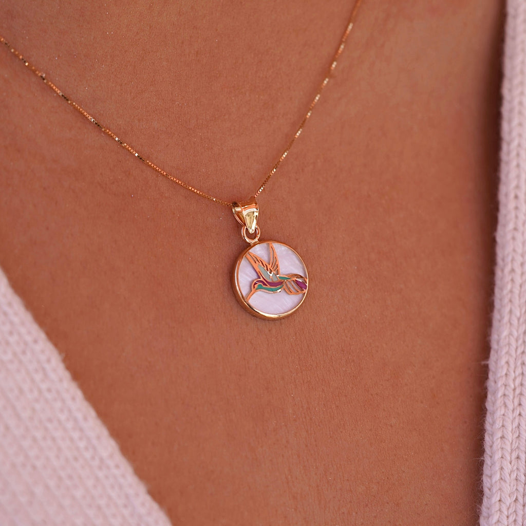 Model wearing the 14K Yellow Gold Hummingbird Medal Pendant on a delicate chain, showcasing the vibrant Mother of Pearl backdrop.