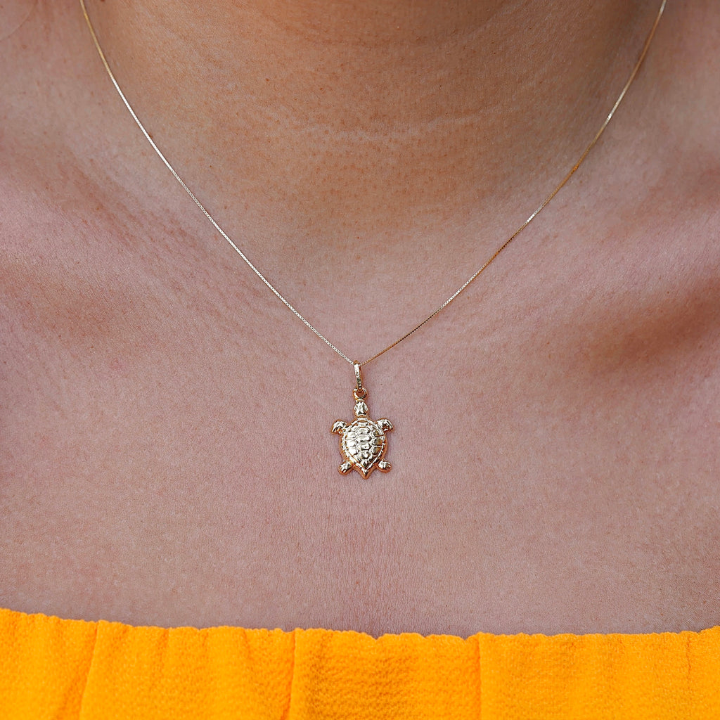 Model wearing the 14K gold turtle charm pendant on a fine chain, showcasing its delicate size and elegant shine on the neckline.