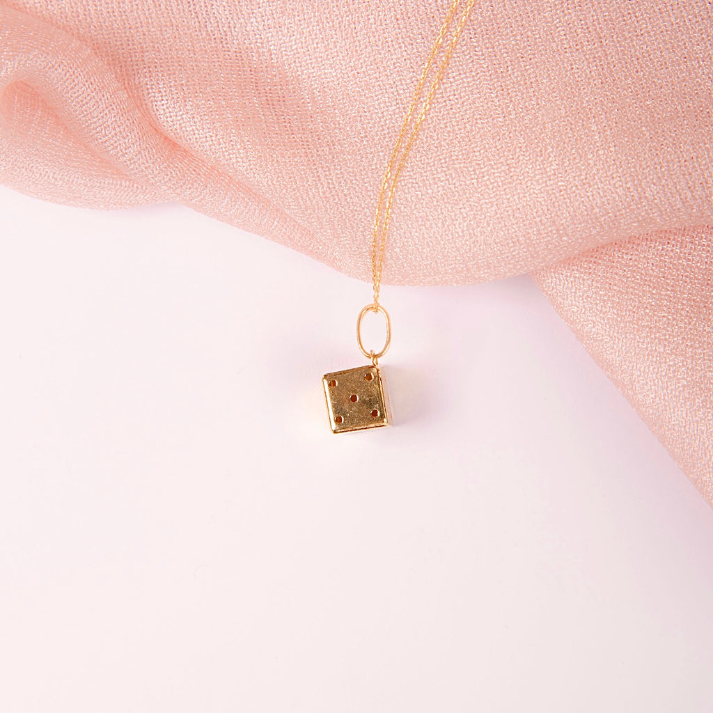 A close-up image of the 14K Yellow Gold Dice Pendant placed against a plain background, showcasing its polished shine and intricate details.