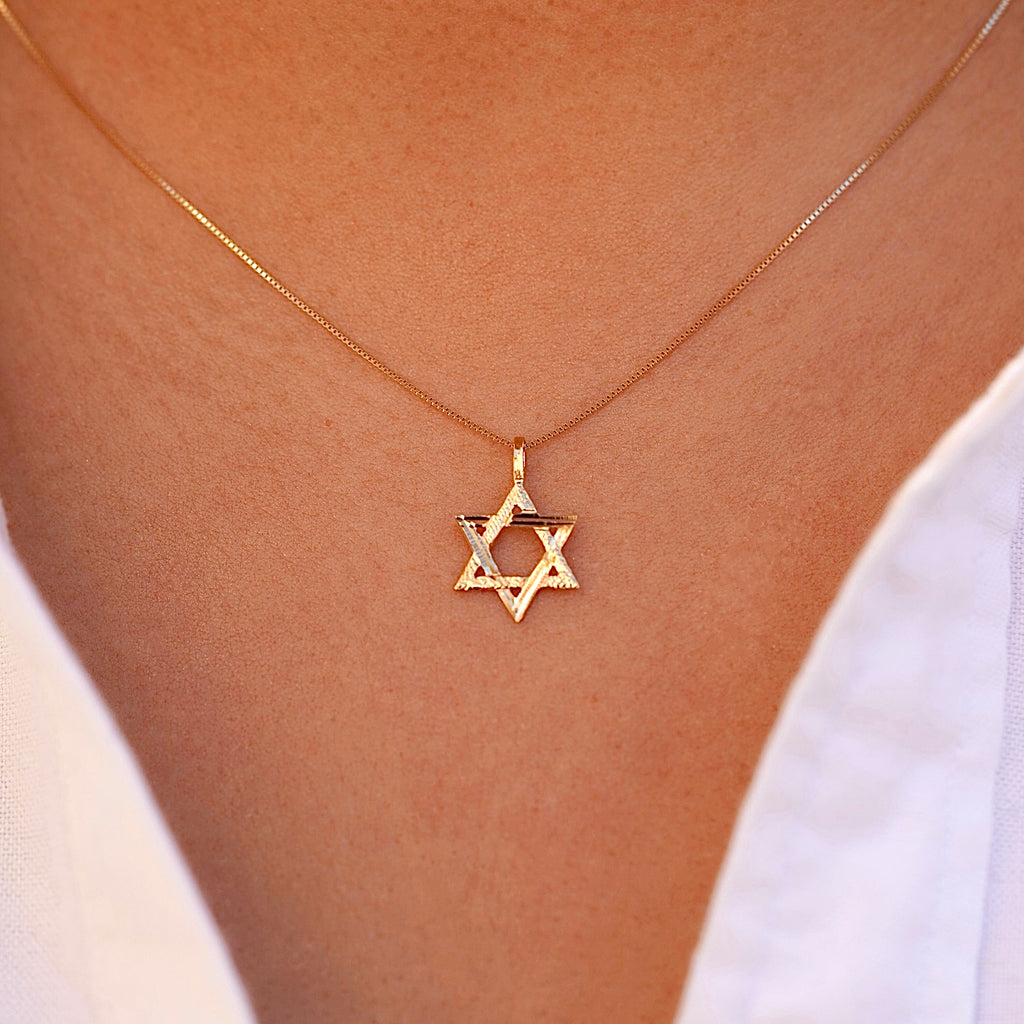 A model wearing the 14K Gold Star of David Pendant on a delicate gold chain, with the pendant resting near their collarbone, adding a subtle touch of faith and elegance to their look.