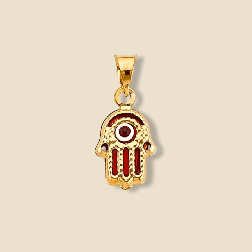 A 14K yellow gold Hamsa pendant with a striking red Evil Eye at its center, displayed on a plain background. The polished gold and vivid red eye create a powerful symbol of protection and style.