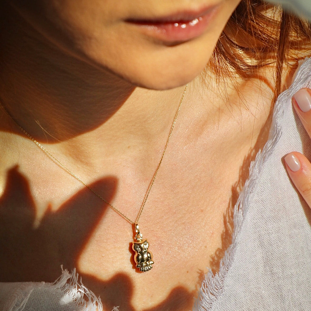 Model wearing the 14K gold owl pendant on a fine chain, with the charm sitting gracefully at the neckline to highlight its elegant silhouette.