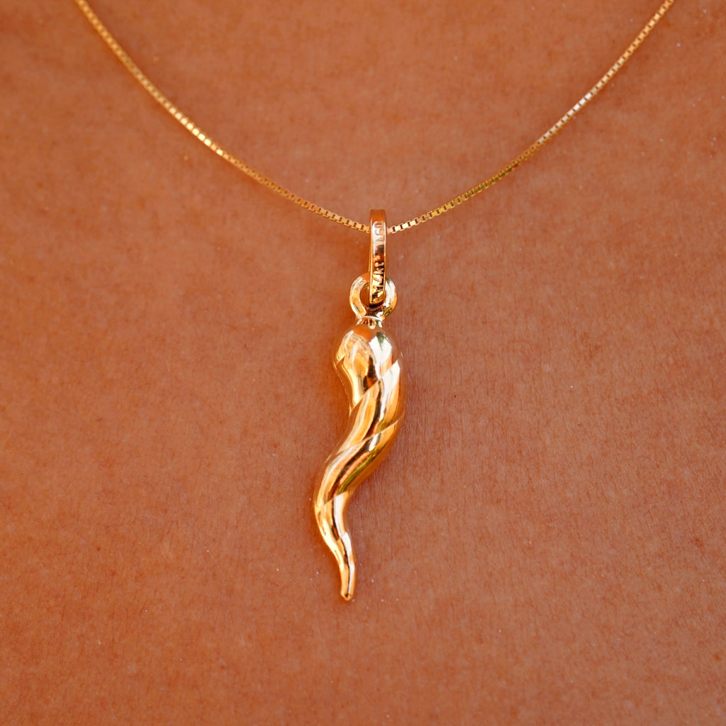 A stylish model wearing the 14K Gold Twisted Cornicello Italian Horn Charm on a delicate gold chain, showcasing its elegant twisted design and radiant gold finish. The pendant rests gracefully on the collarbone, adding a touch of Italian heritage and timeless charm to the outfit.