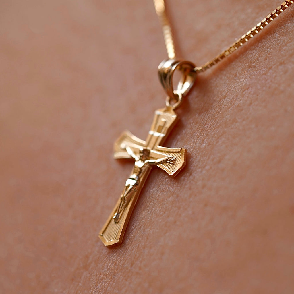 A model wearing the 14K Yellow Gold Crucifix Cross Pendant on a gold chain, highlighting its religious significance and elegant craftsmanship.