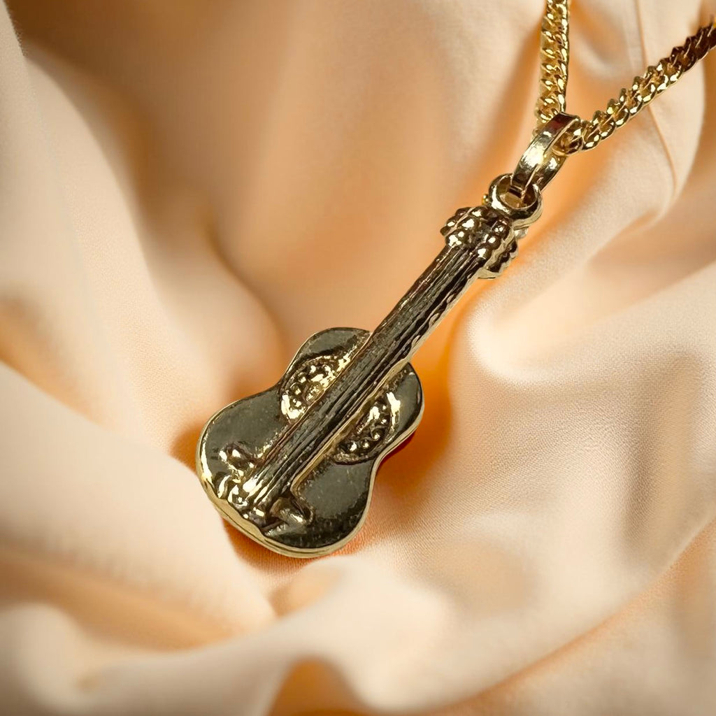 14K Gold Cello Pendant displayed on a textured, off-pink linen cloth, highlighting its polished shine and delicate string details.
