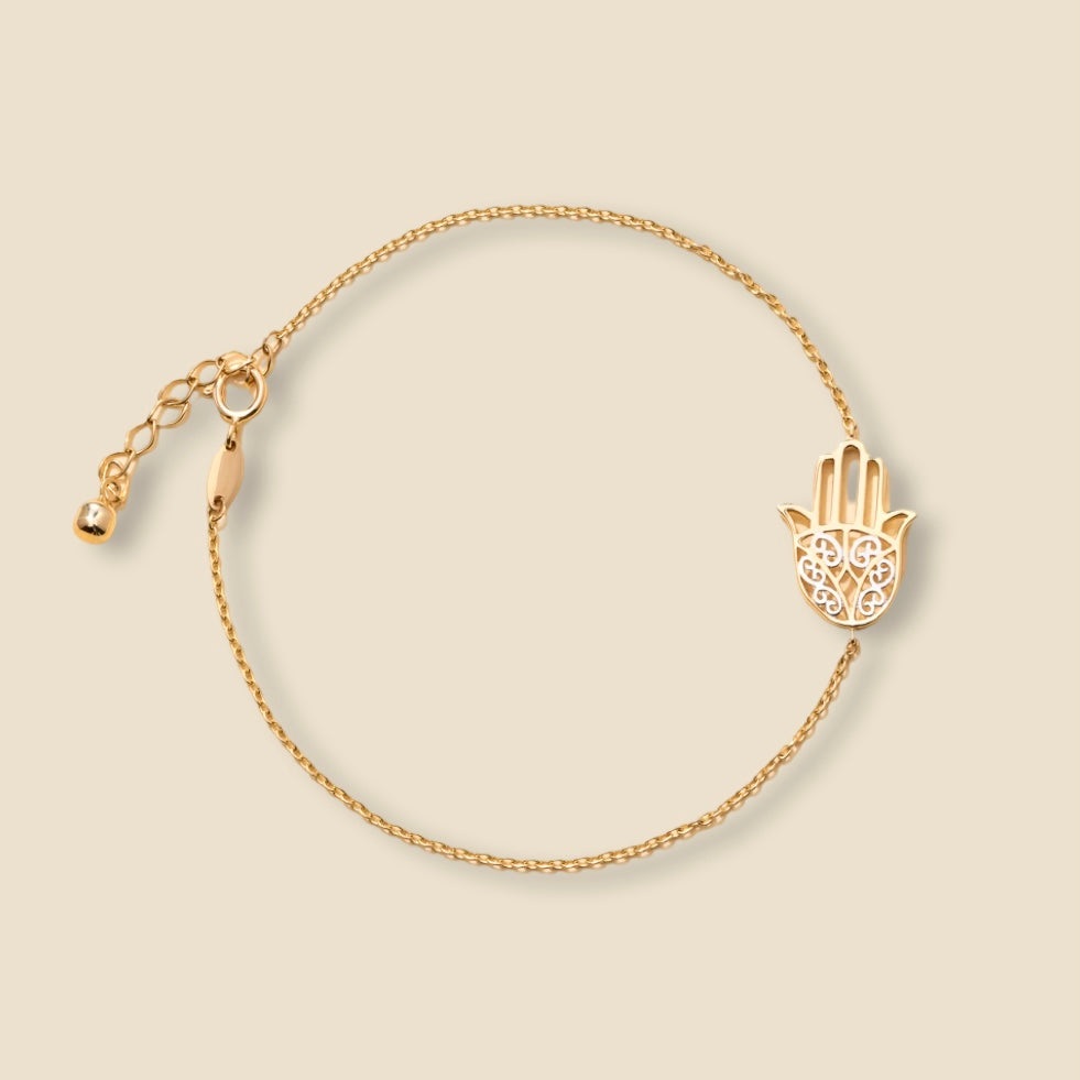 Close-up of a 14K yellow gold light bracelet laid flat on a plain background, showing delicate chain details.