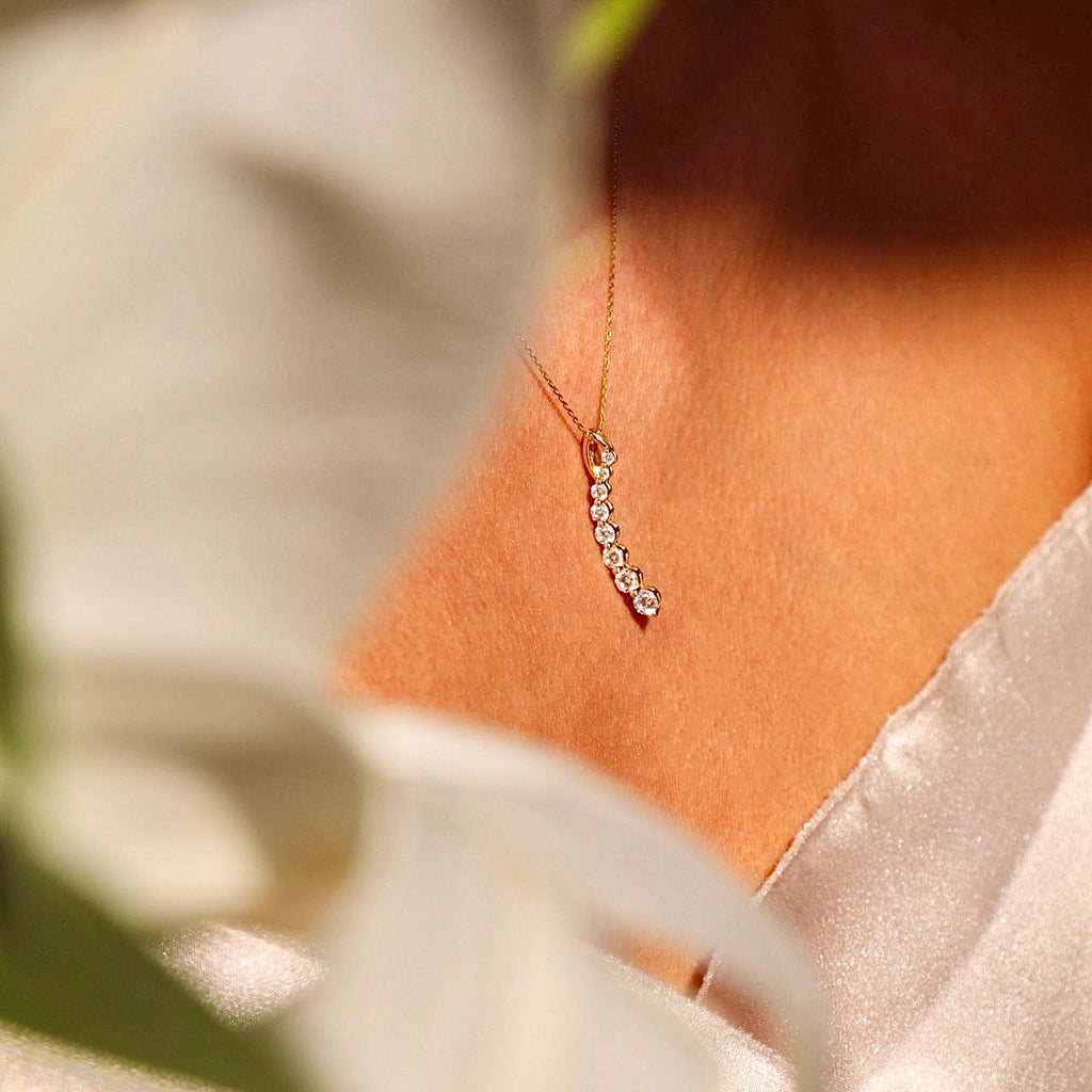 A close-up of a model wearing a dainty 14K gold Italian horn pendant on a delicate chain, adding a touch of elegance and meaning to her outfit.