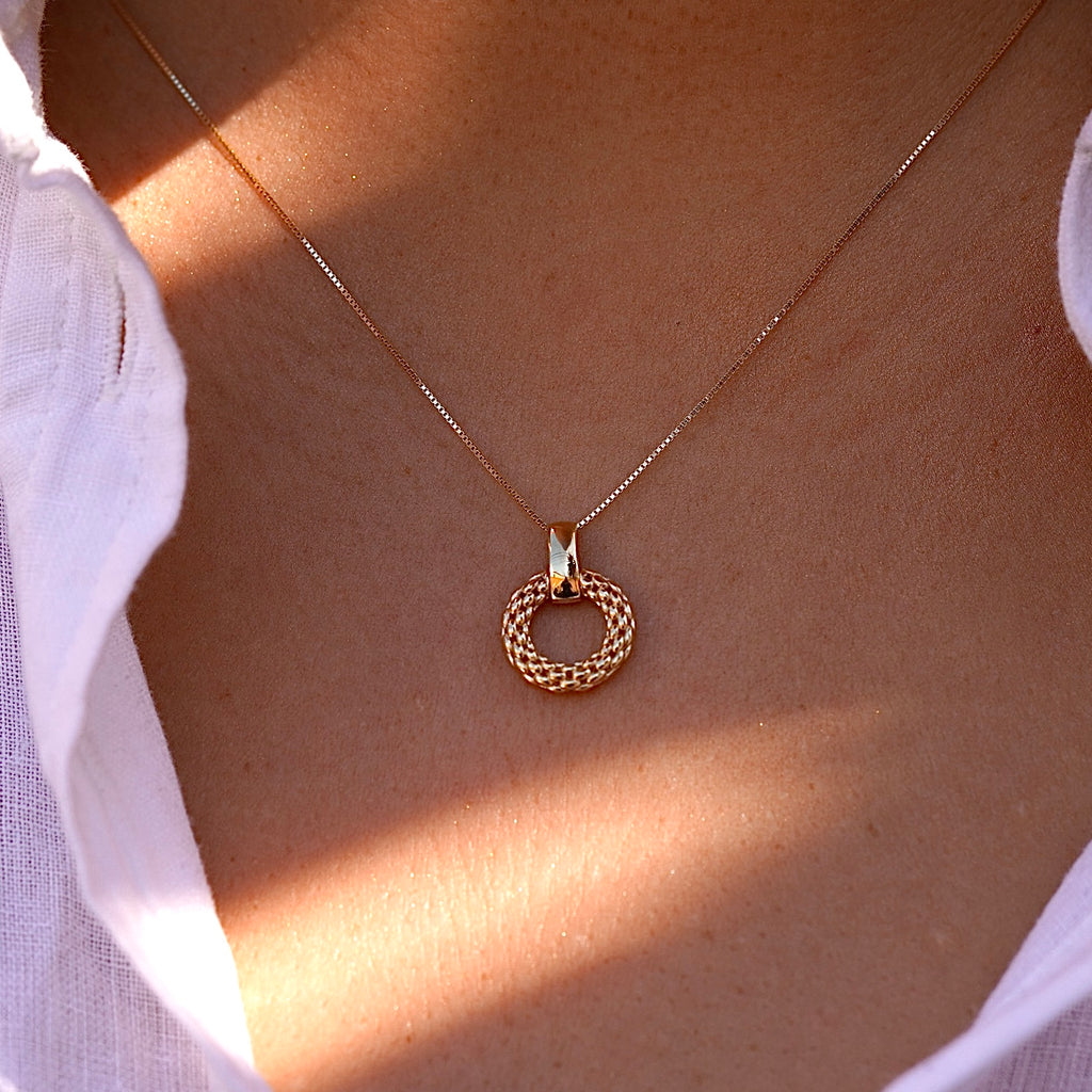 A woman wears the 14K gold mesh pendant on a dainty gold chain, the intricate filigree design resting gracefully against her collarbone. The lightweight and elegant pendant adds a timeless touch to her outfit.