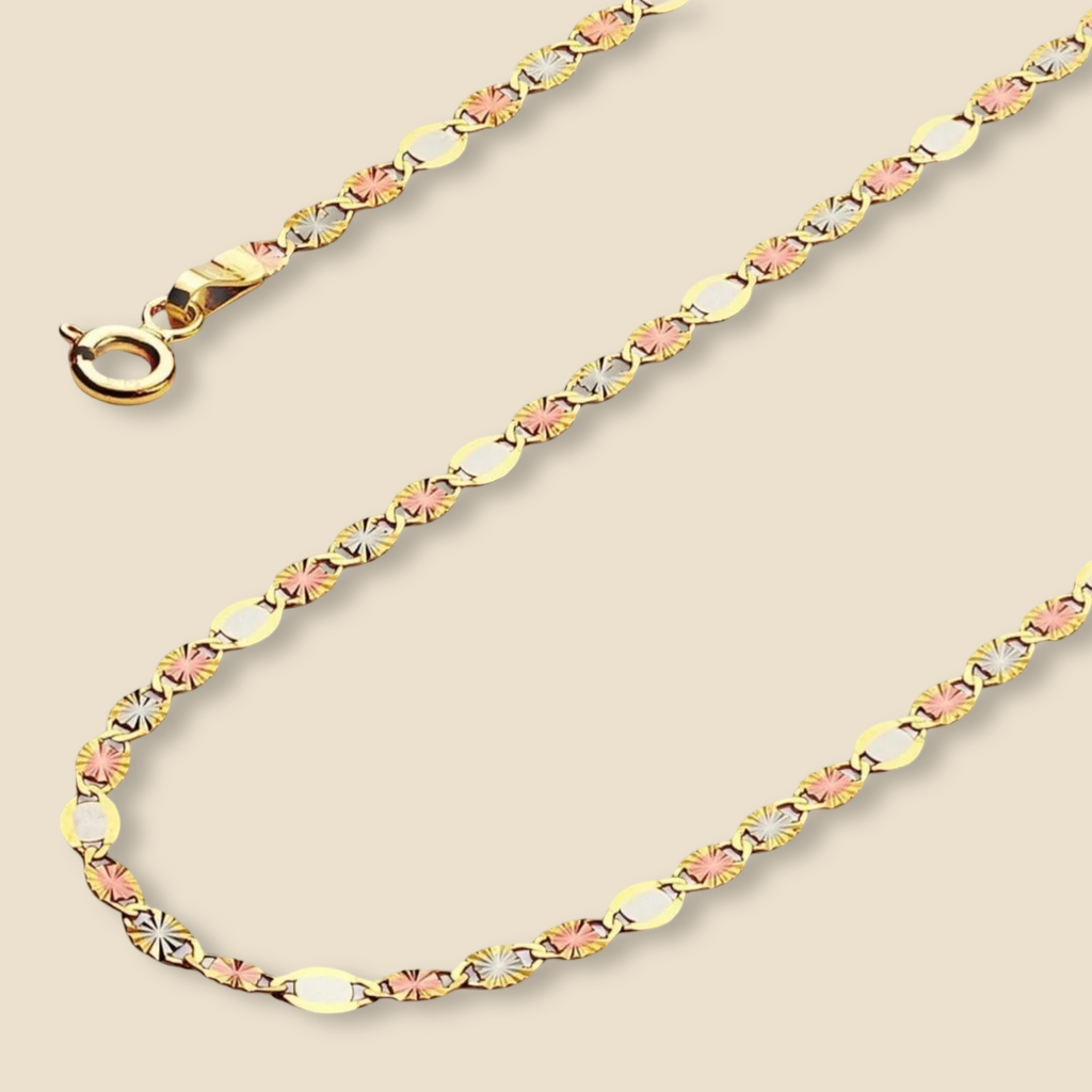 Flat 14K tri-color Valentino star chain necklace laid in a straight line on a plain background, highlighting the shine and elegant diamond-cut star links.