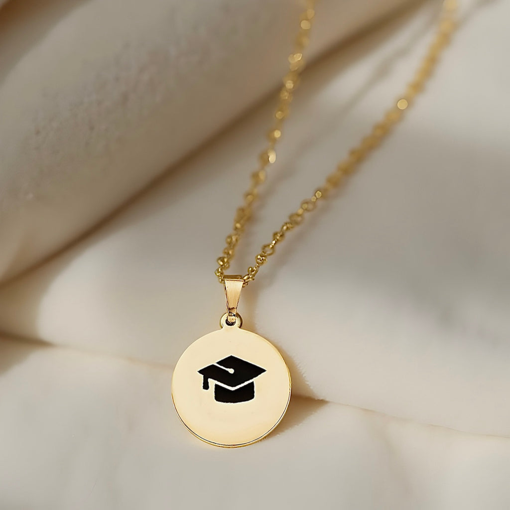 Elegant 14K Gold Graduation Pendant resting on soft off-white fabric, showcasing its refined craftsmanship and symbolic design.