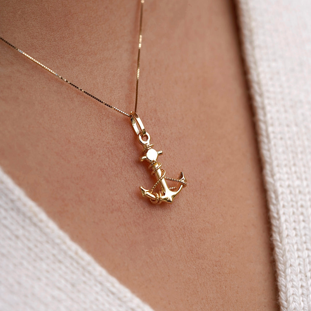 Model wearing a 14K gold anchor pendant on a delicate chain, showcasing the dainty nautical charm against the neckline for an elegant, maritime-inspired look.