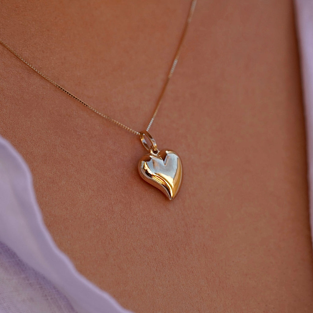A model wearing the 14K Yellow Gold Hollow Heart Pendant on a fine chain, elegantly styled against her collarbone, highlighting its minimalist beauty.
