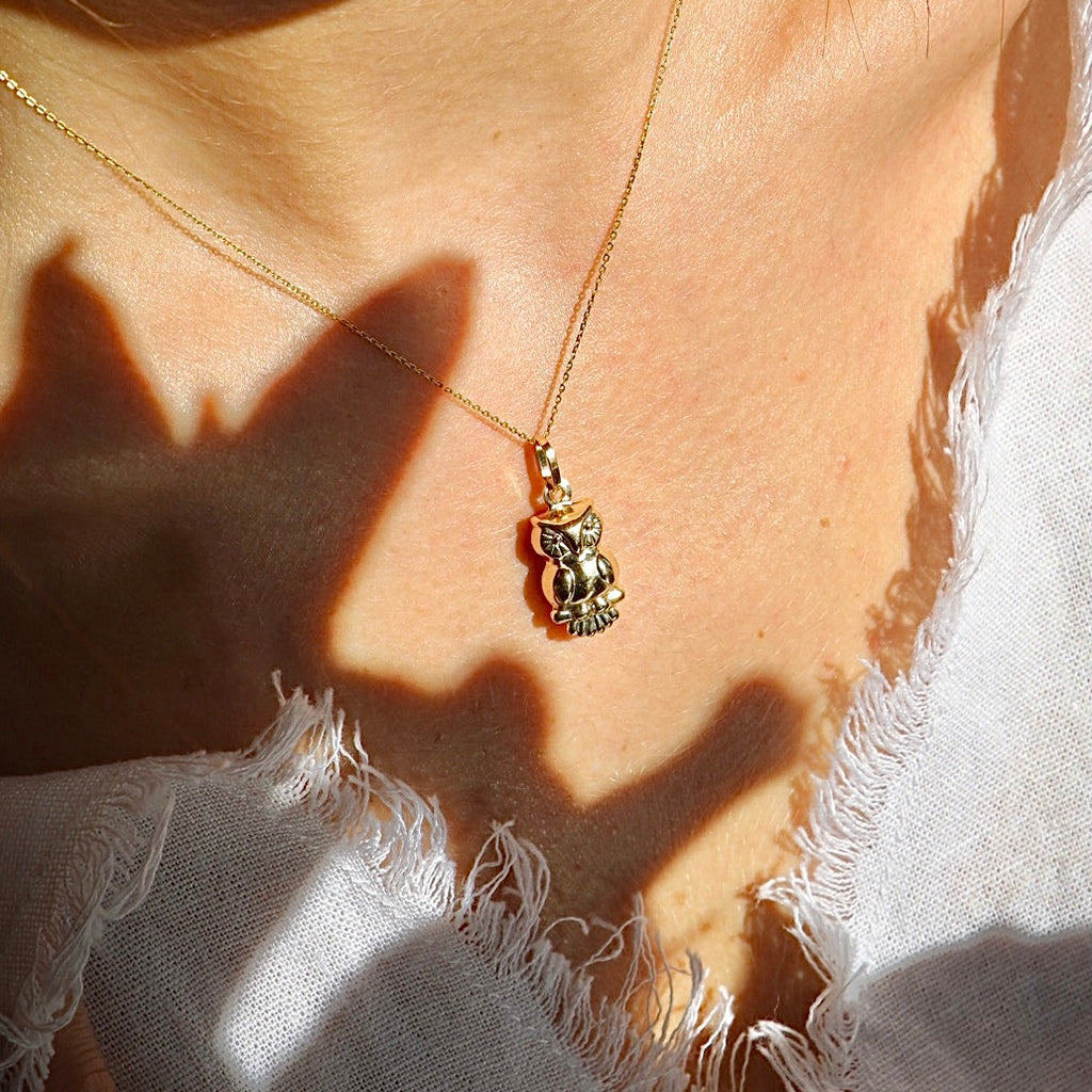 Model wearing the 14K gold owl pendant on a fine chain, with the charm sitting gracefully at the neckline to highlight its elegant silhouette.