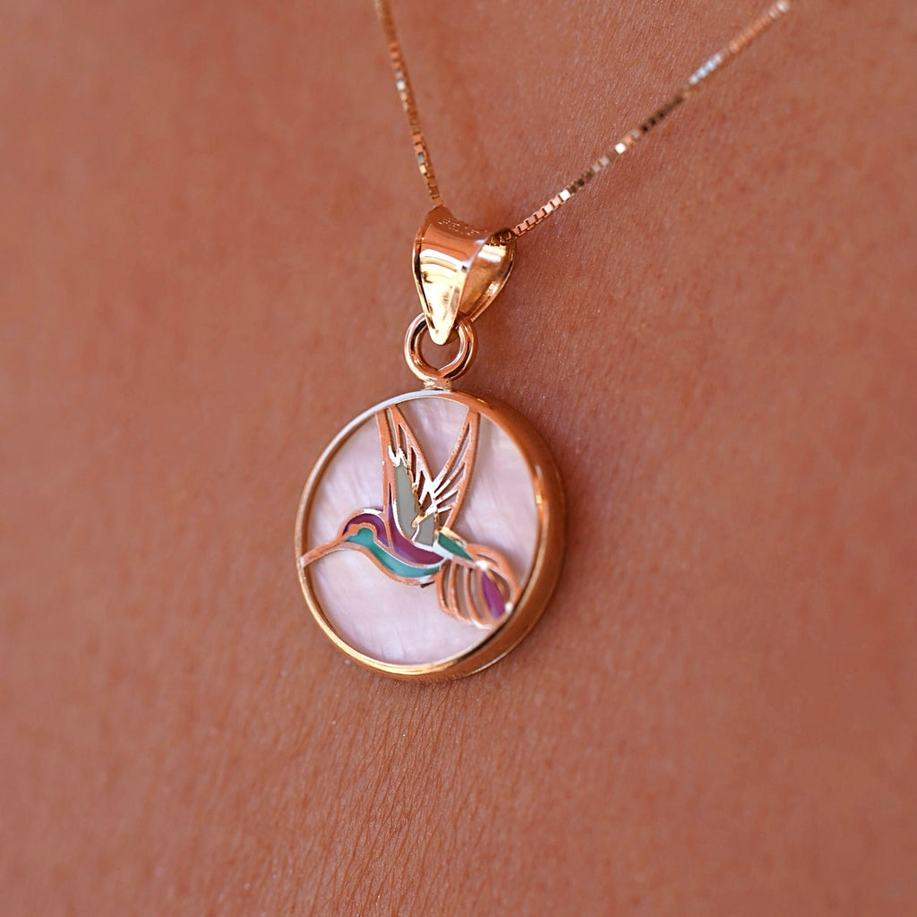 Model wearing the 14K Yellow Gold Hummingbird Medal Pendant on a delicate chain, showcasing the vibrant Mother of Pearl backdrop.