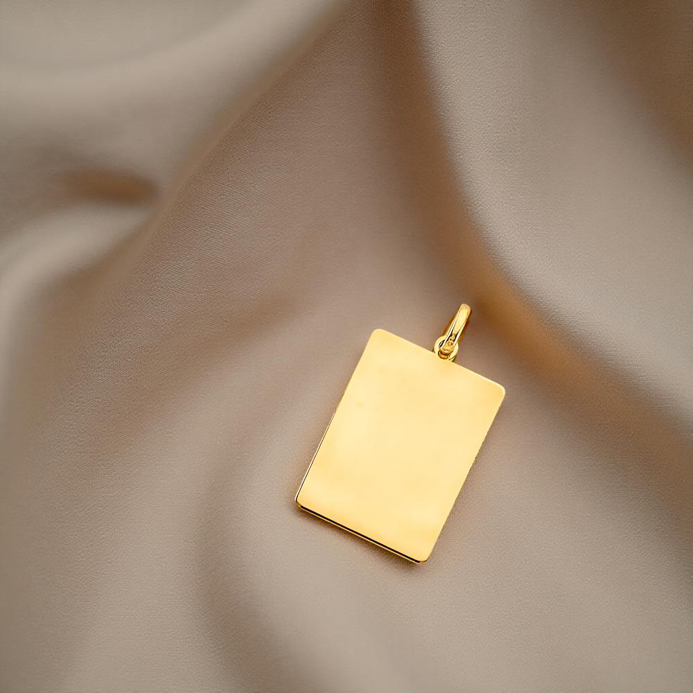 A polished 14K yellow gold engravable pendant resting on a soft, neutral-toned fabric, with gentle natural lighting highlighting the clean, flat surface ideal for personalization.