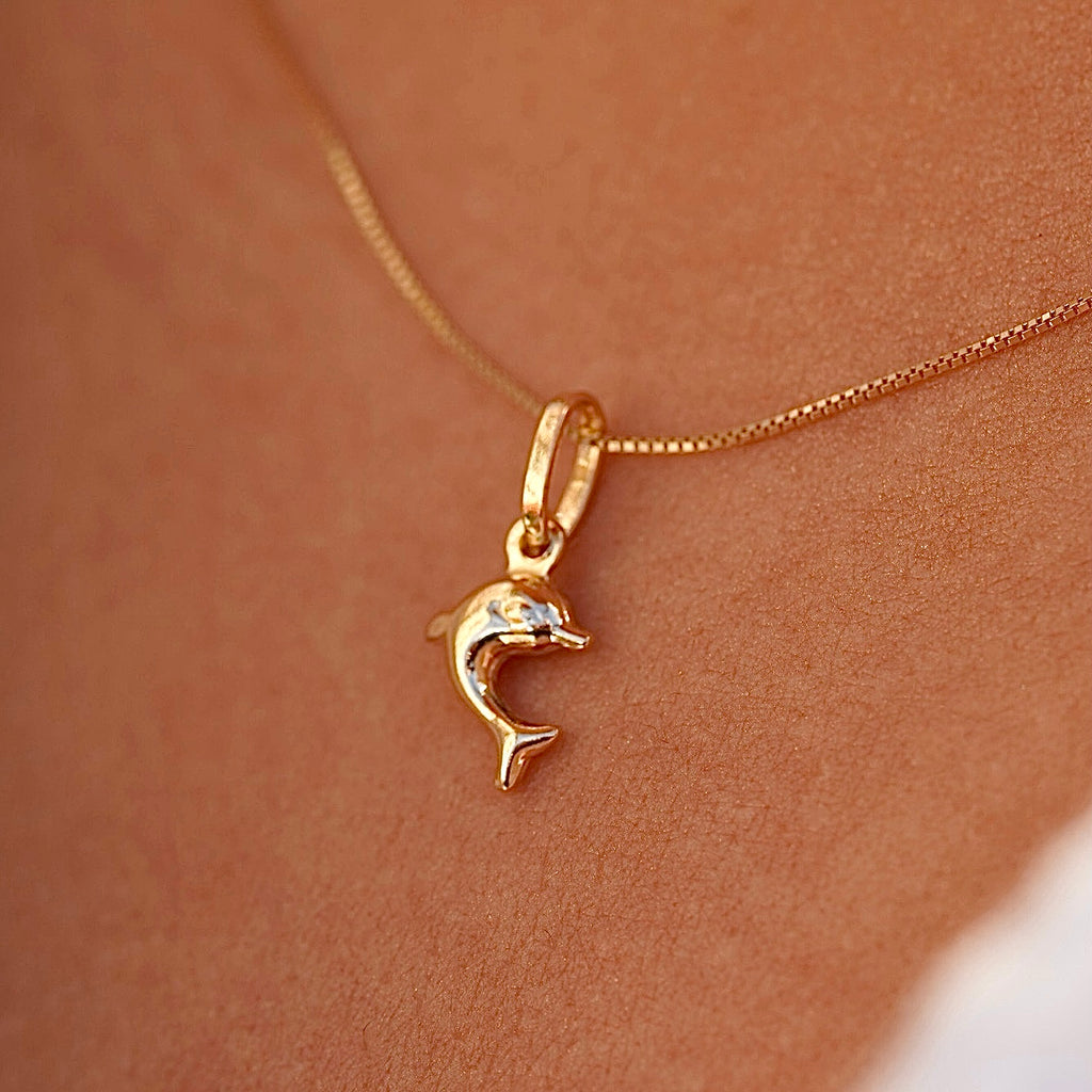 Model wearing the 14K yellow gold dolphin pendant on a fine chain, demonstrating its dainty size and stylish appeal.