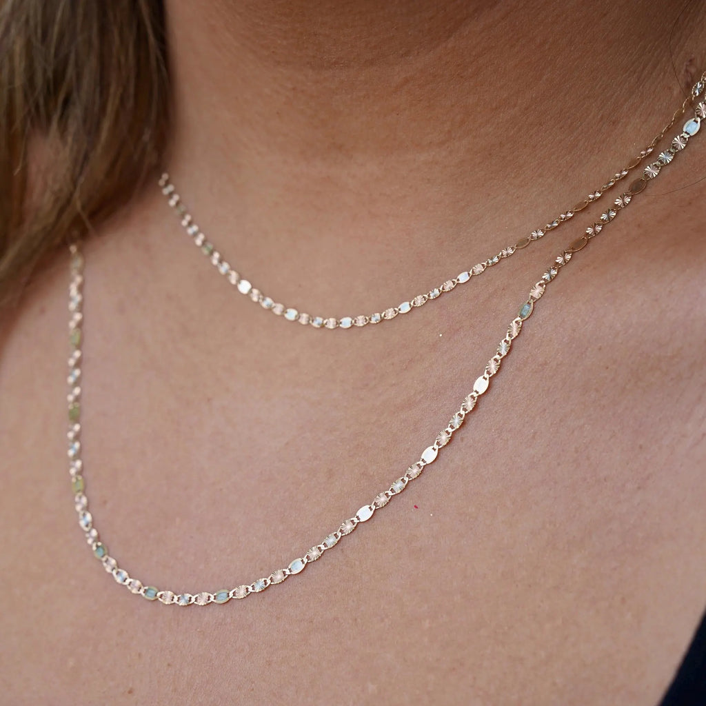 A model elegantly wearing the 14K solid gold Valentino chain necklace, showcasing its refined, lightweight design. The 2mm chain drapes gracefully around the neck, highlighting its polished gold shine. Perfect for everyday wear or special occasions, this Italian-made chain exudes timeless sophistication and versatility.